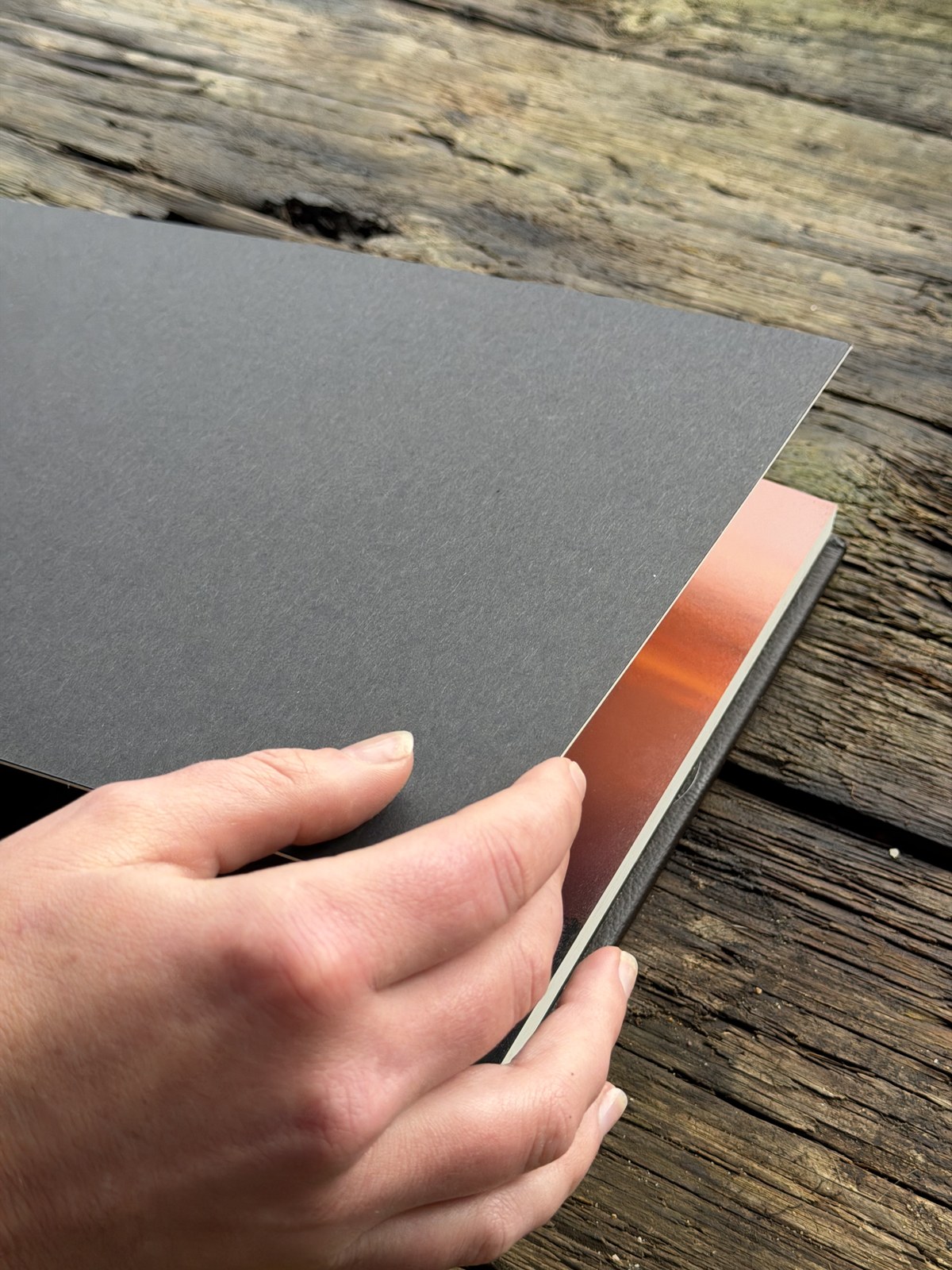 Close-up of an album page turning against a weathered wooden table